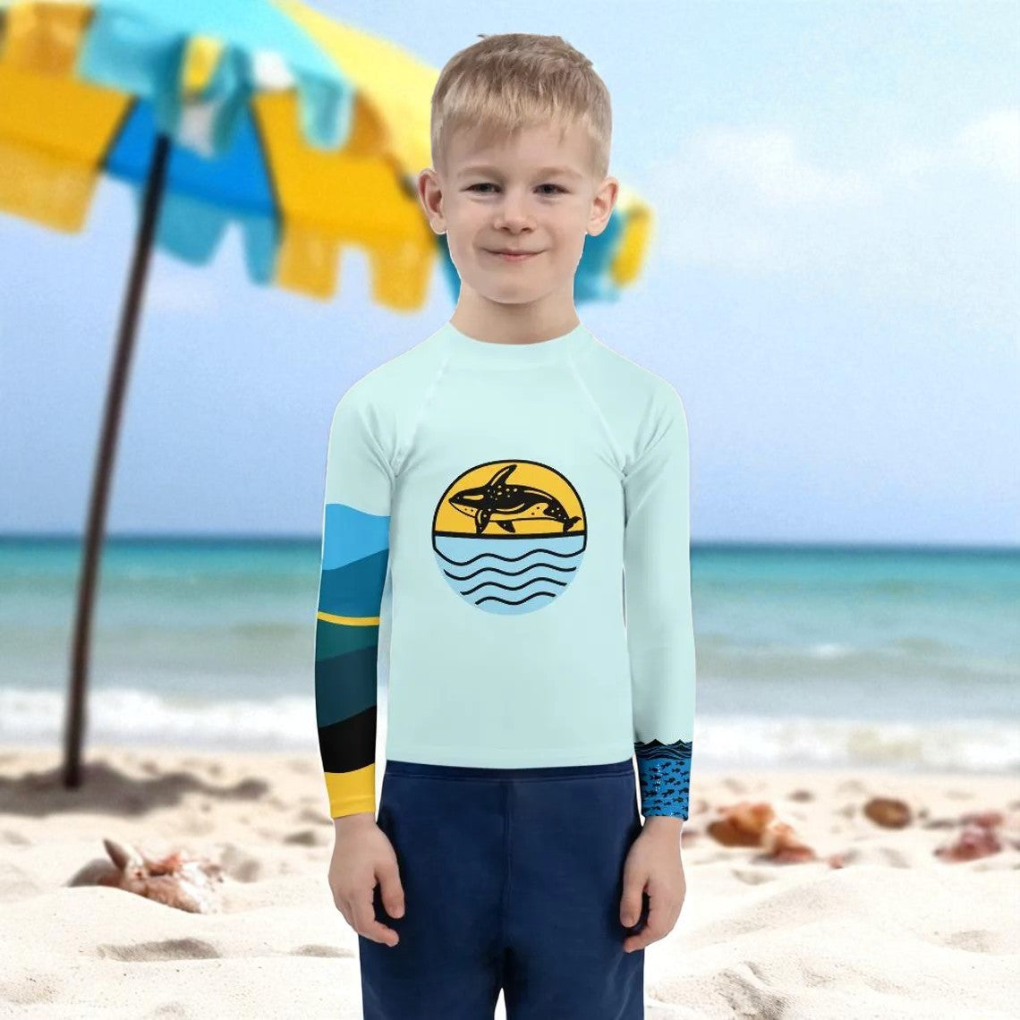Child wearing a long-sleeve rash guard shirt with a dolphin design on a beach