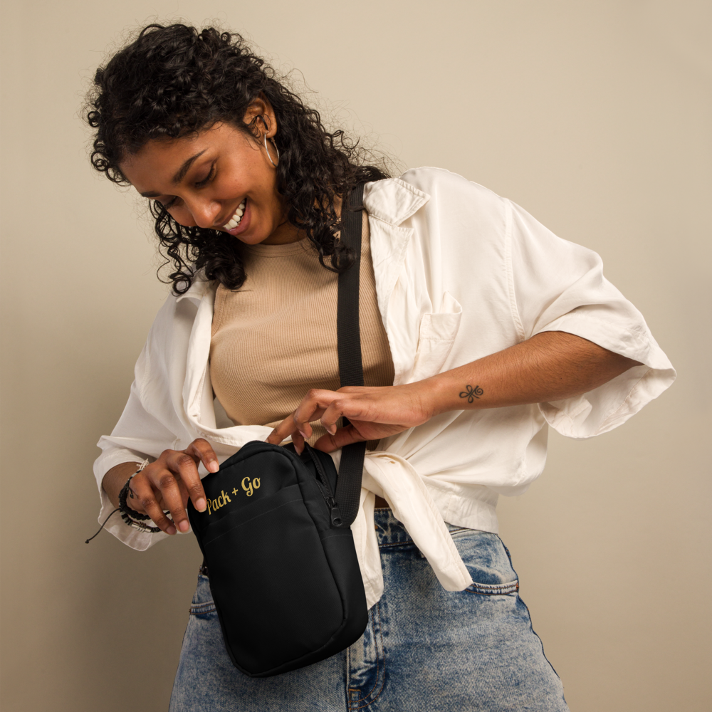 Woman holding a black bag with 'Pack & Go' branding against a beige background