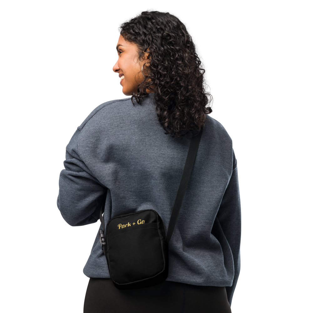 Person wearing a gray sweatshirt with a black crossbody bag on a white background