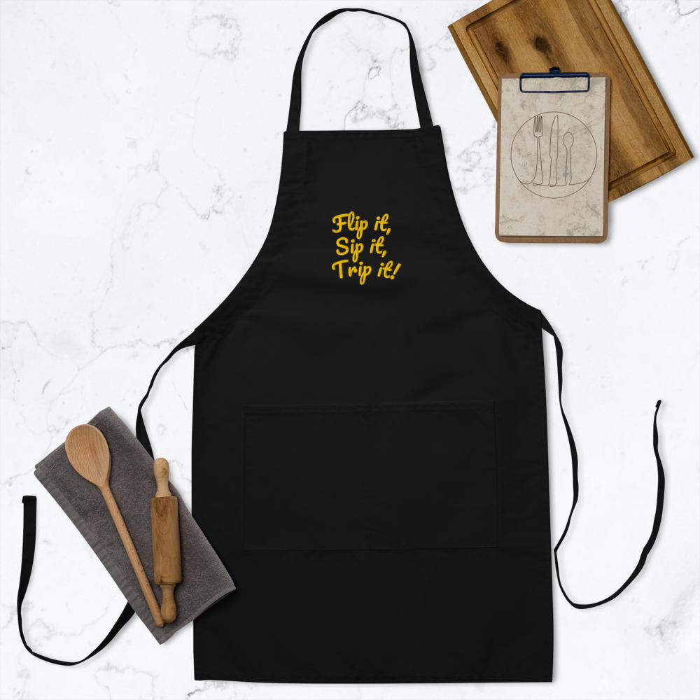 Black apron with yellow text on a white surface with kitchen items.