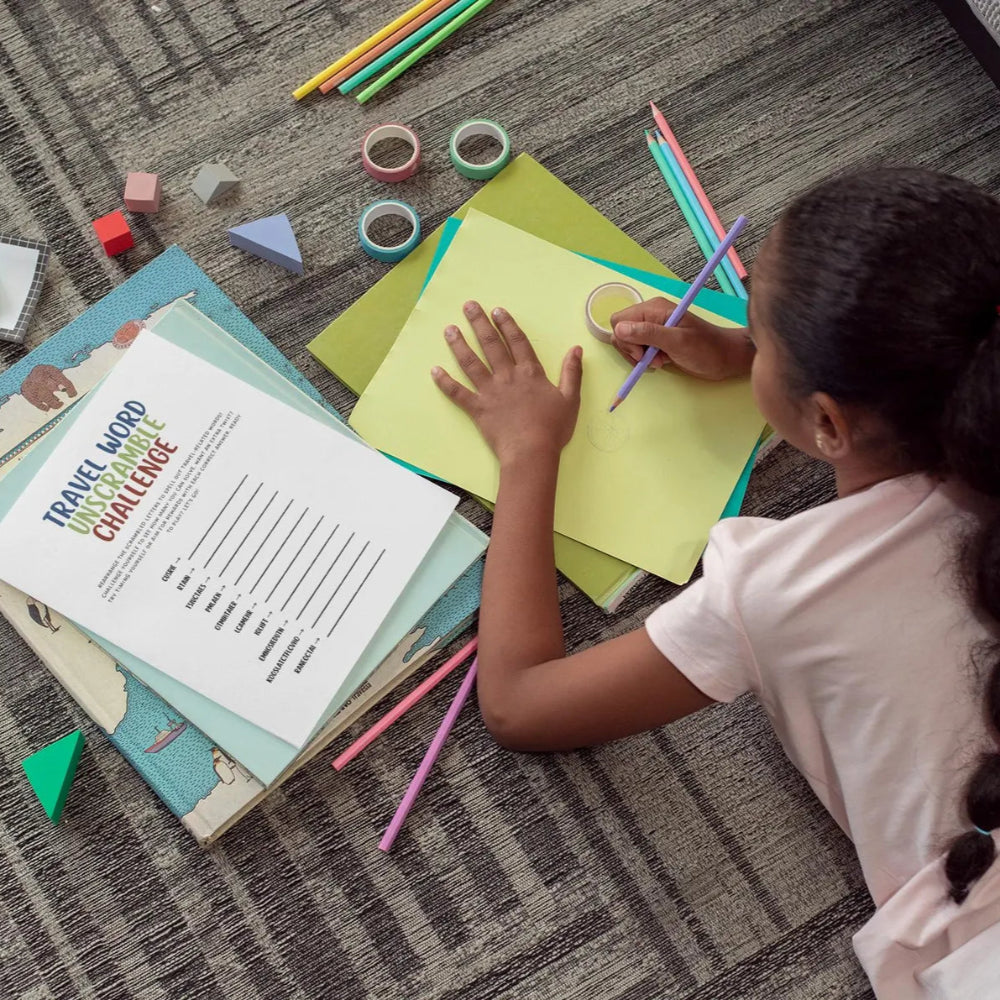 Child sitting on a carpeted floor with educational materials and coloring supplies.