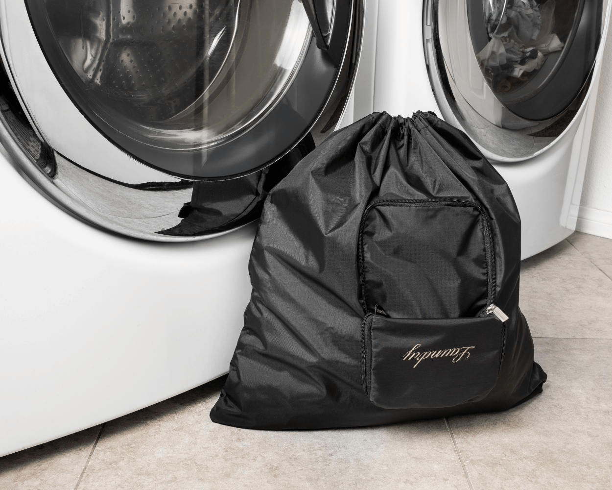 Black laundry bag with 'Laundry' branding in front of a washing machine.