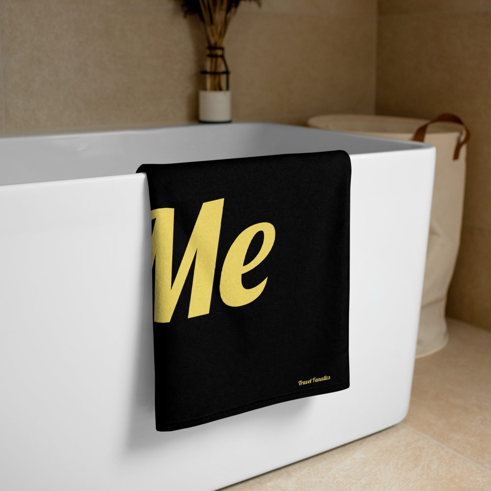 Black towel with 'Me' in gold letters draped over a white bathtub.