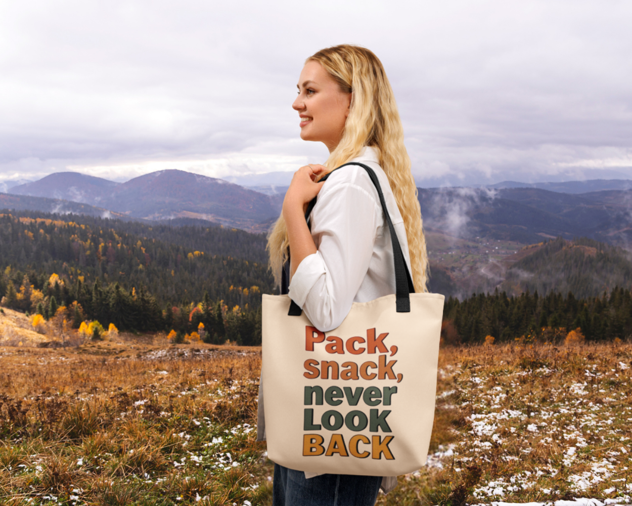 Woman holding a tote bag with text in a scenic outdoor setting