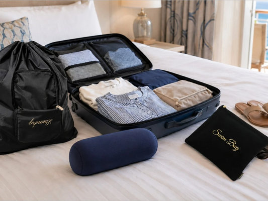 Cruise packing essentials with suitcase, laundry bag, wet bag, travel pillow, sunscreen, sandals, and folded outfits