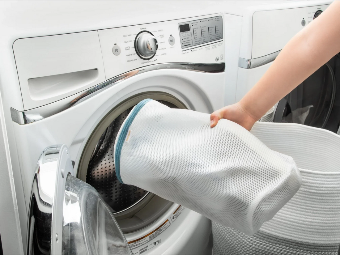 Sneakers inside a mesh laundry bag being placed into a washing machine