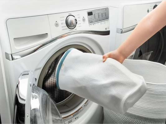 Sneakers inside a mesh laundry bag being placed into a washing machine