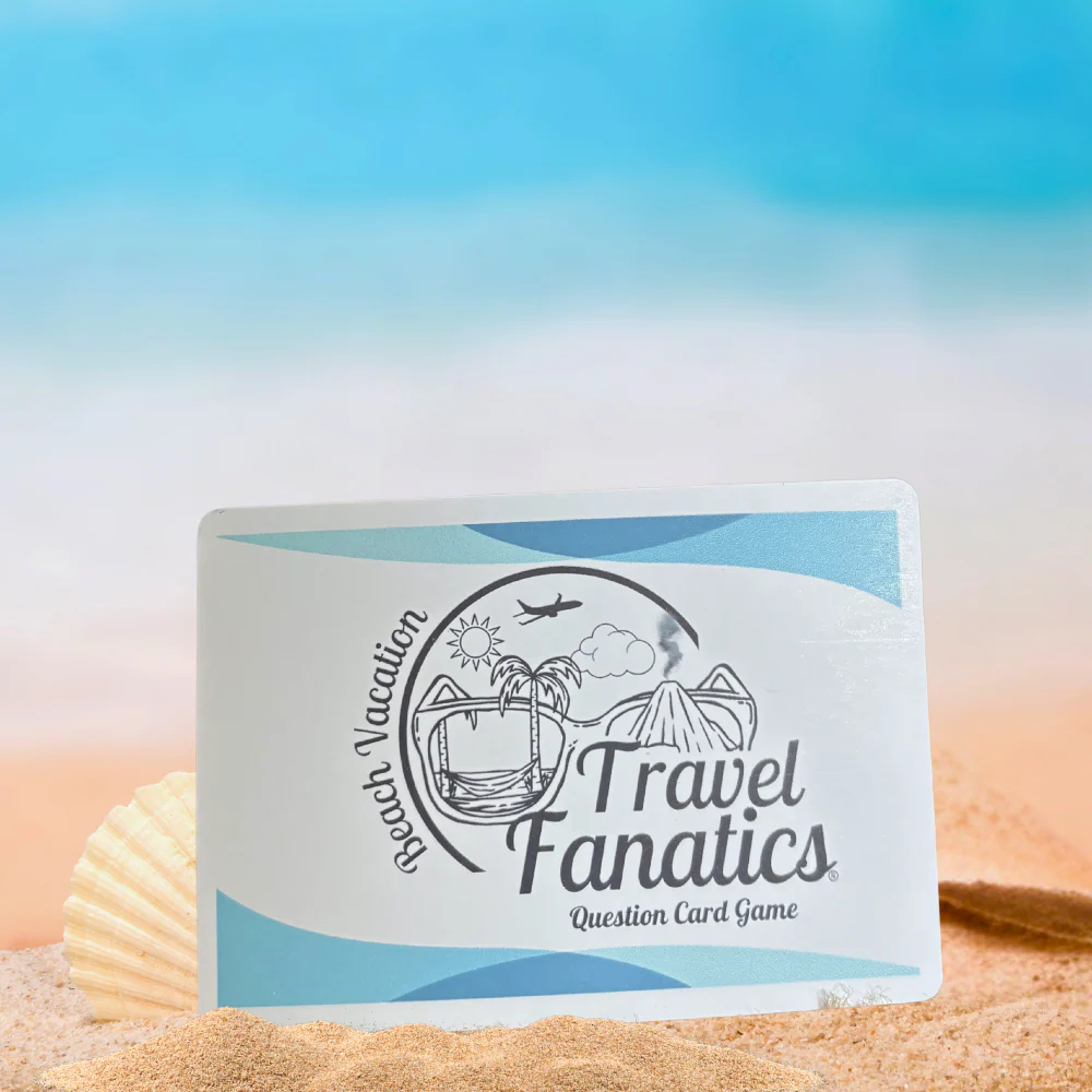Travel Fanatics question card game packaging on sand with a beach background

