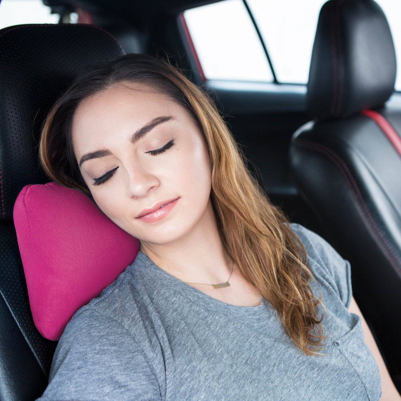 Woman using a pink car neck pillow in a vehicle

