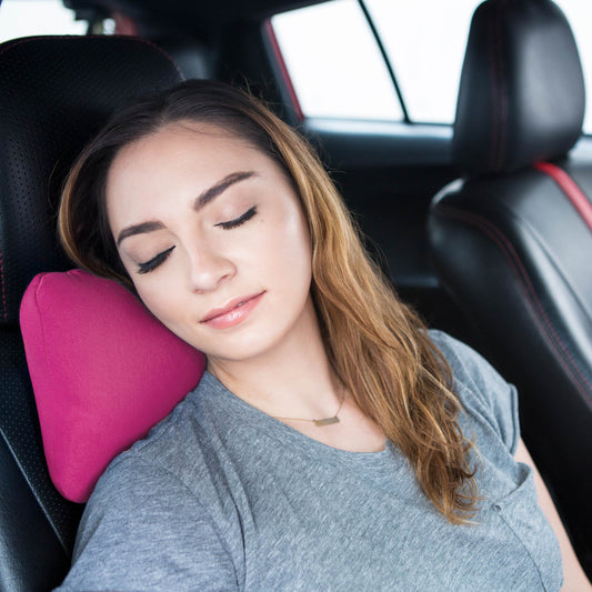 Woman using a pink car neck pillow in a vehicle

