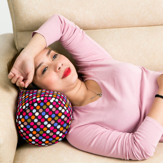 Woman lying on a couch with a colorful polka dot pillow

