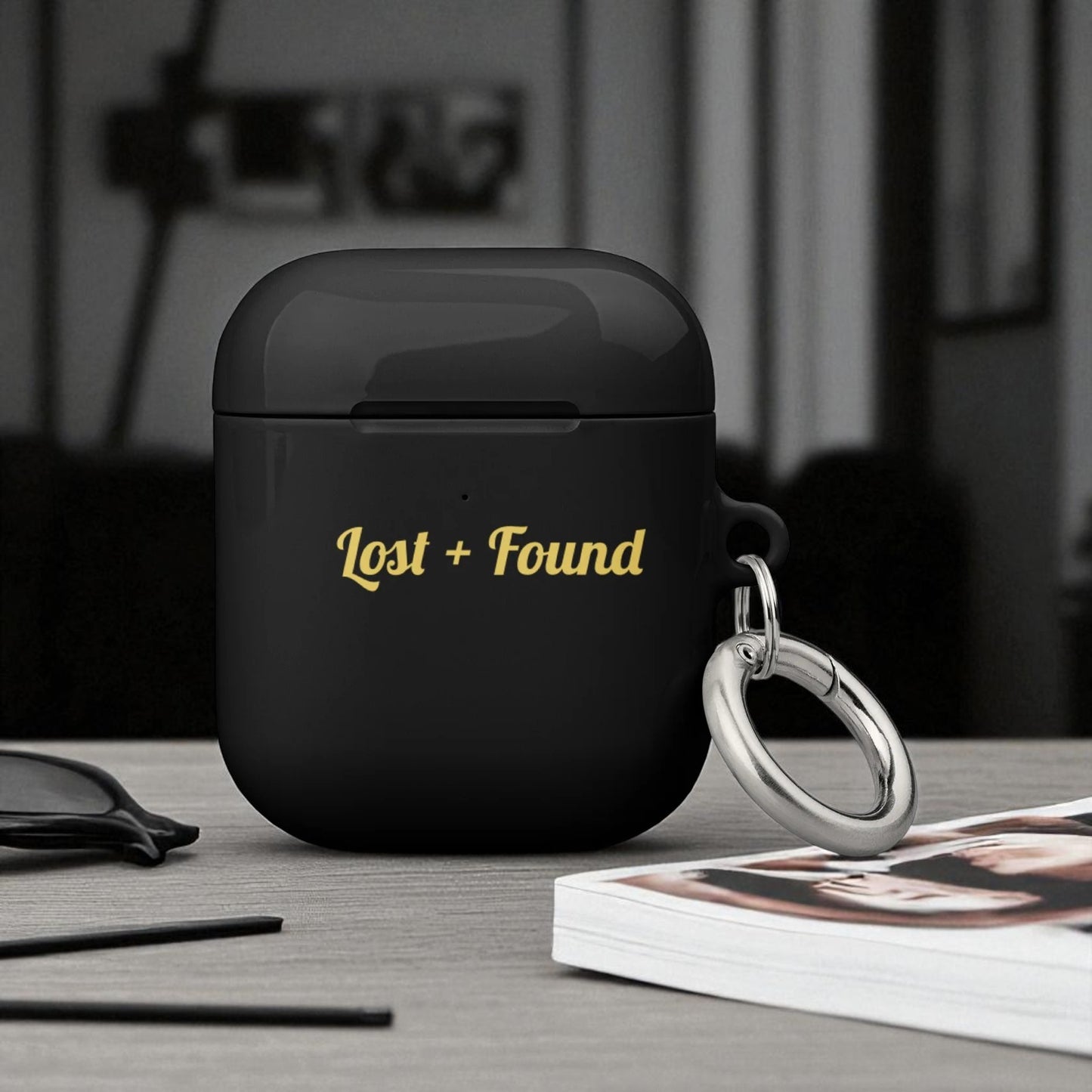 Black wireless earbud case with 'Lost + Found' text on a table.

