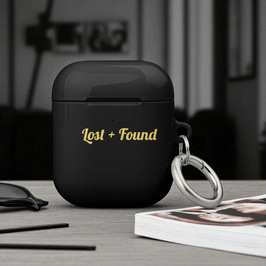 Black wireless earbud case with 'Lost + Found' text on a table.

