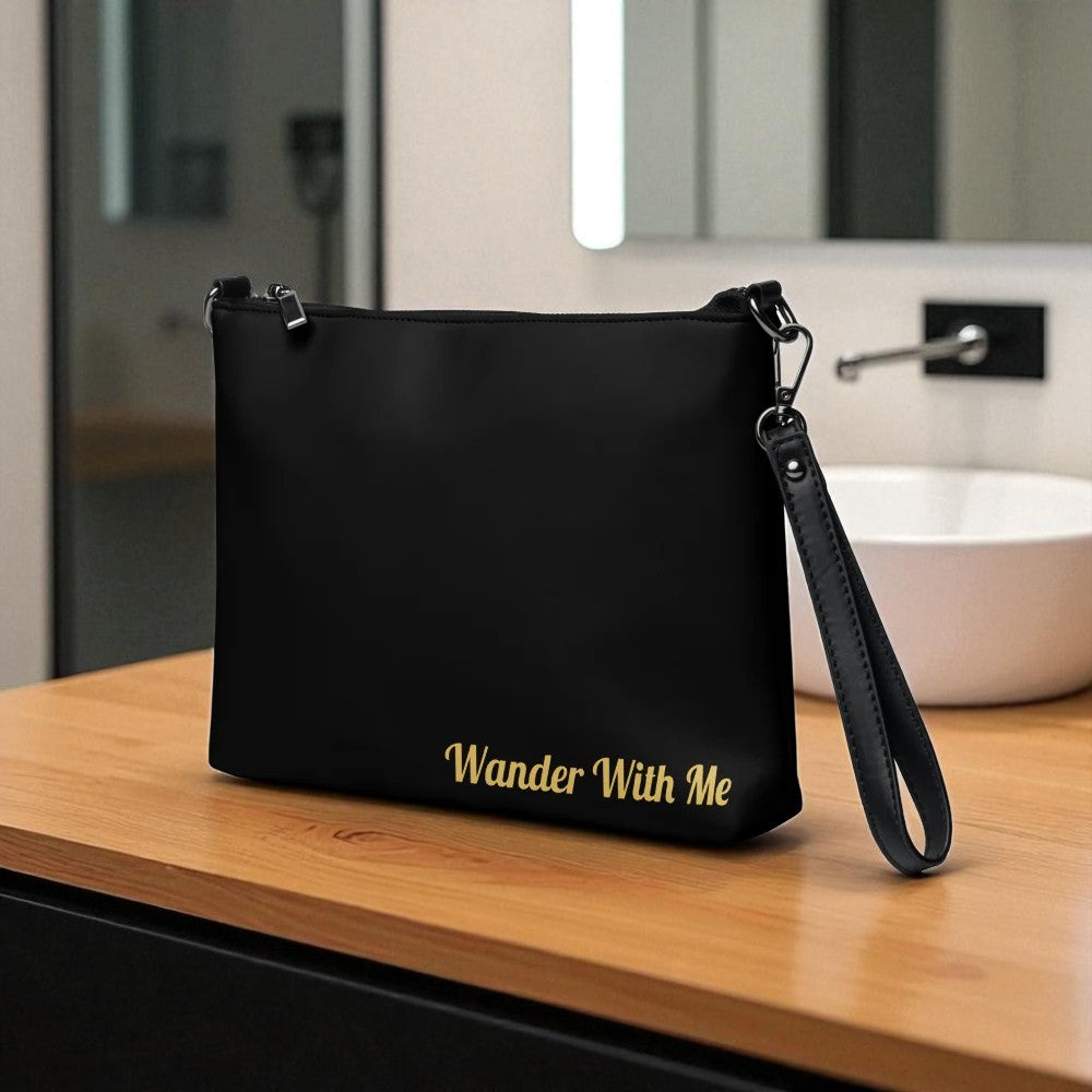 Black bag with 'Wander With Me' text on a wooden surface in a bathroom setting

