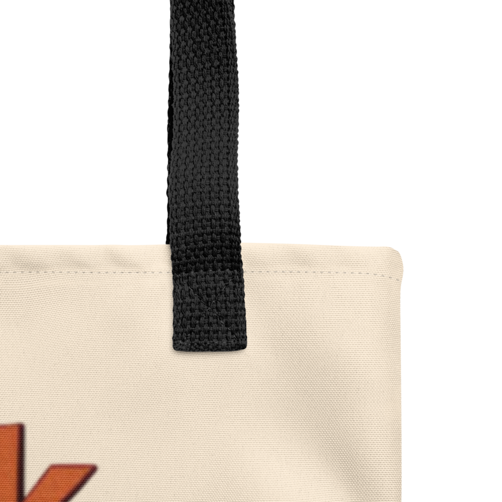 Close-up of a beige tote bag with a black strap and orange letter 'K'.

