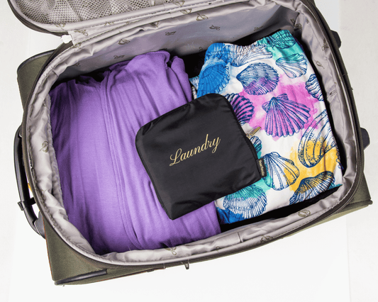 Open suitcase with folded clothes and a black 'Laundry' bag inside
