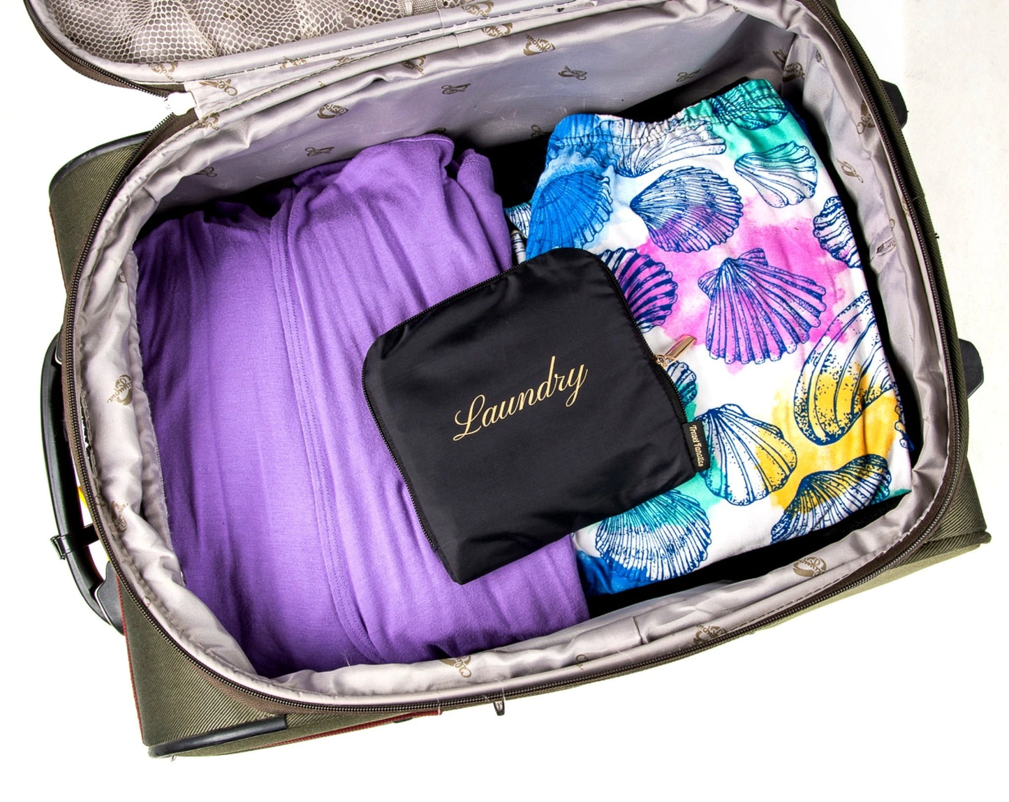 Open suitcase with purple garment, colorful shell-patterned fabric, and black 'Laundry' bag.

