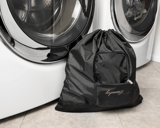 Black laundry bag with 'Laundry' branding in front of a washing machine.